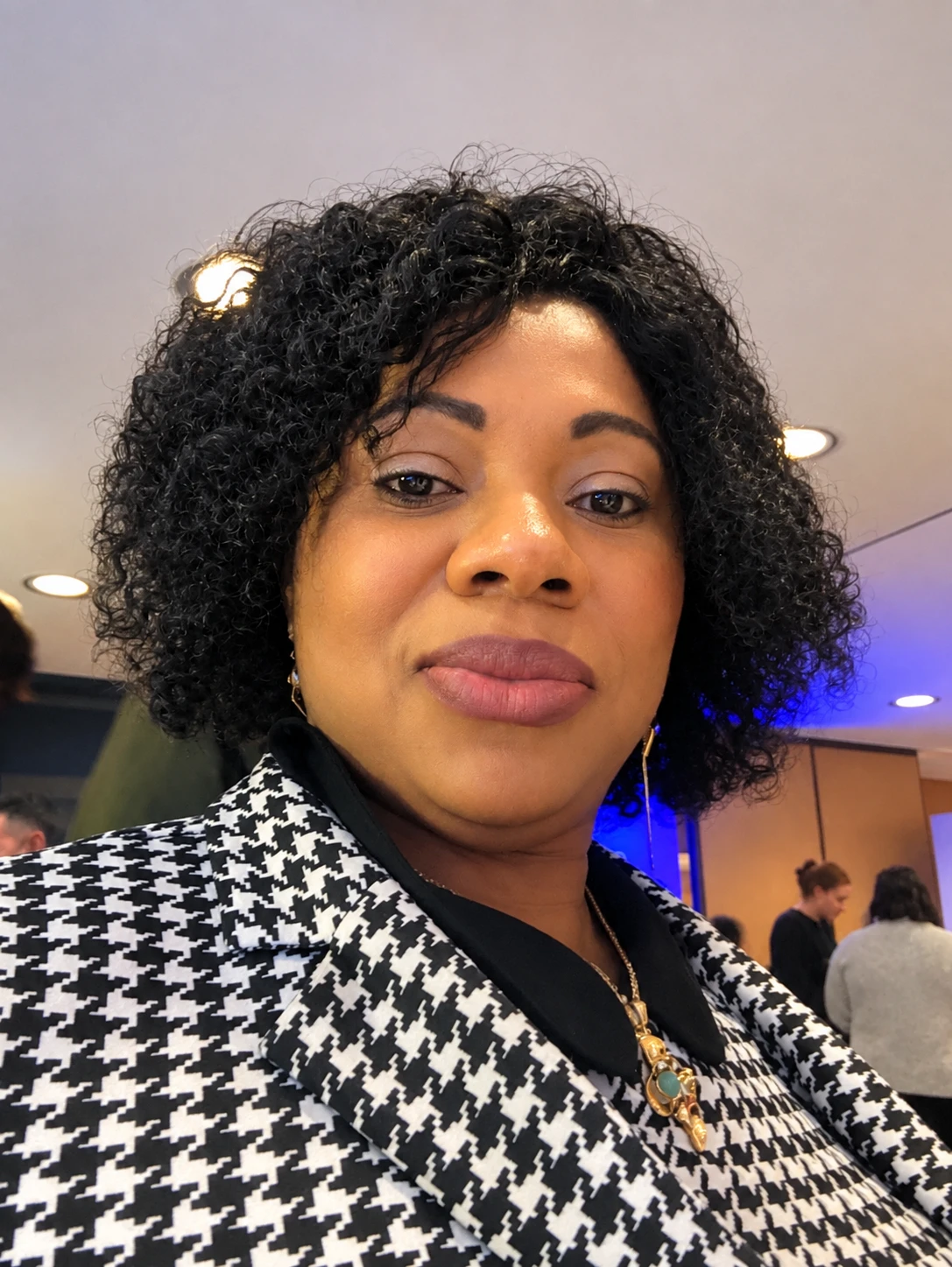 Dr. Judith Eta, DNP, PMHNP-BC, smiling warmly in a black-and-white houndstooth jacket